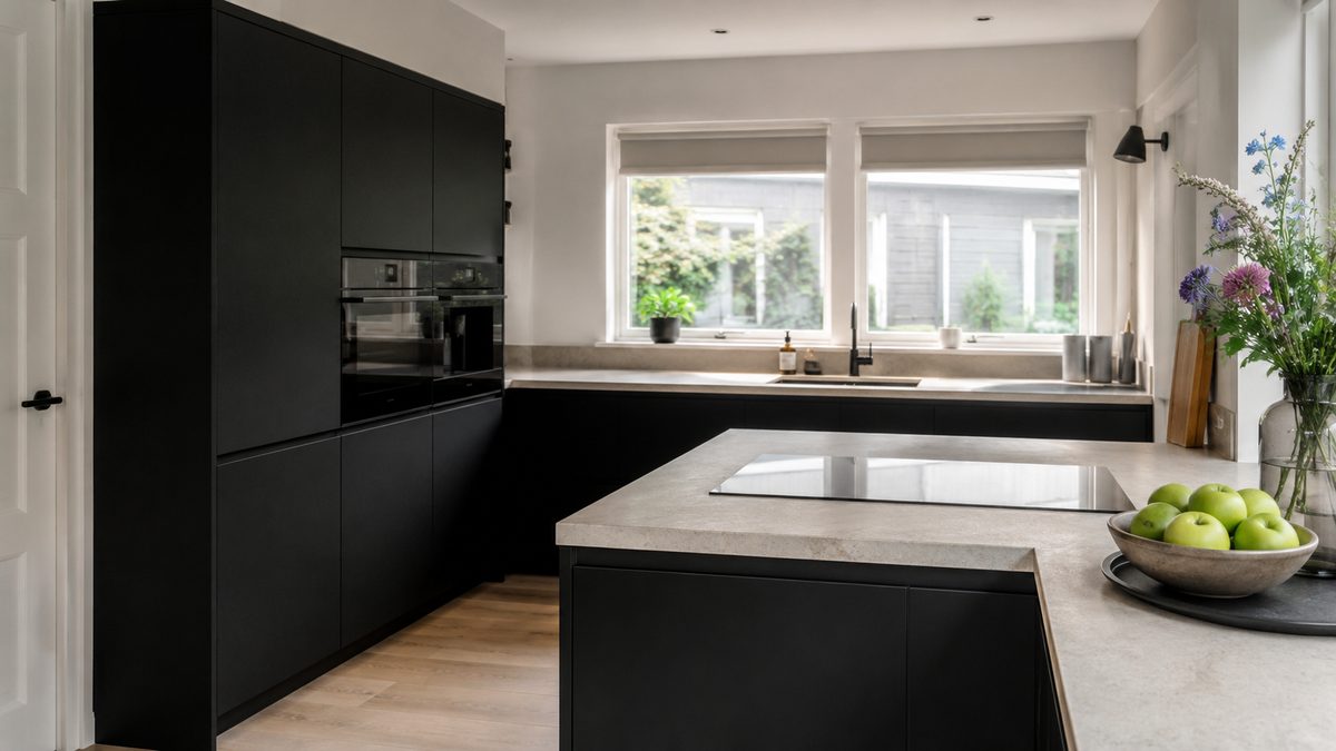 Strakke zwarte keuken met een licht werkblad bij het raam