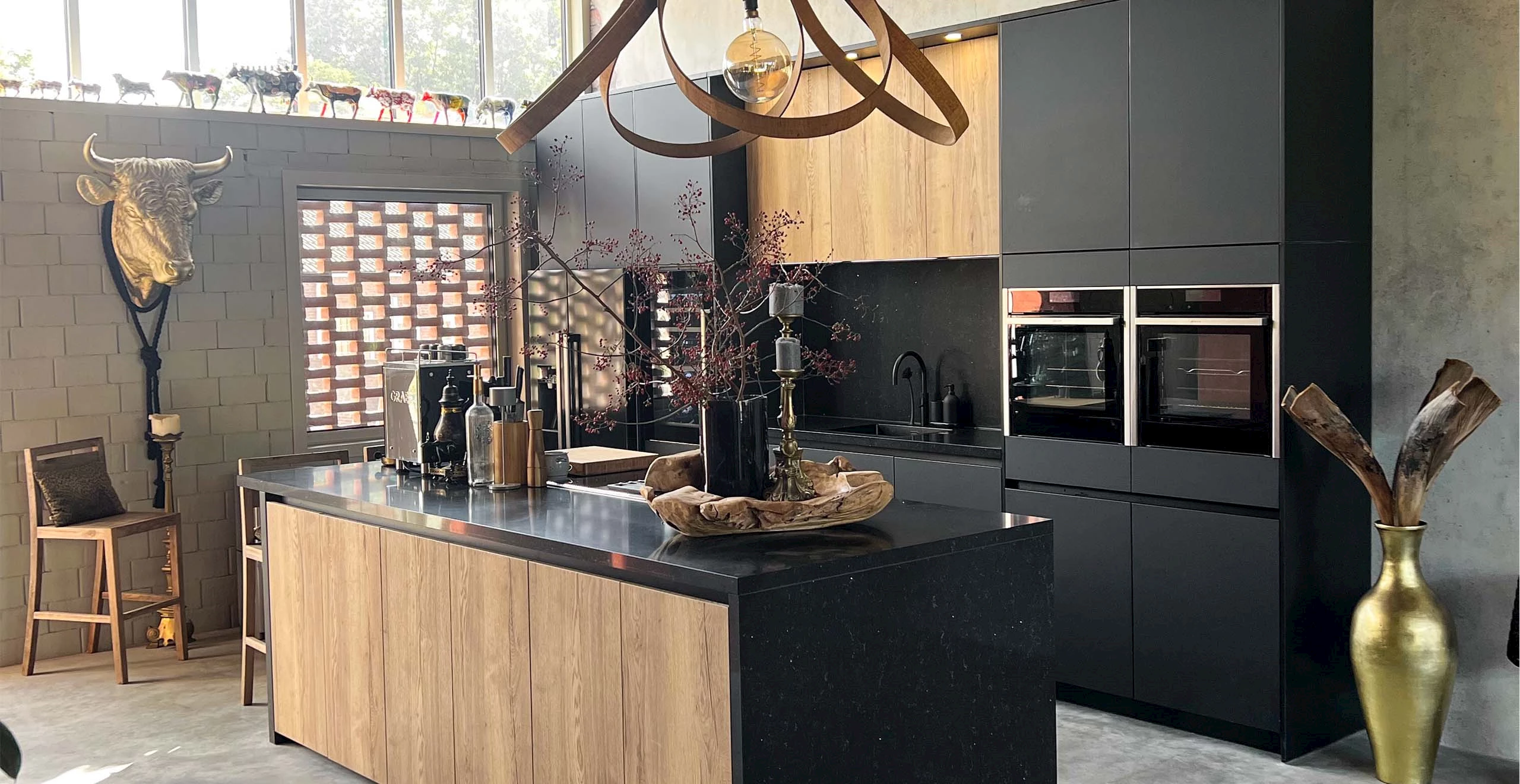 Industriële keuken met houten kookeiland, mat zwarte fronten en bakstenen muur