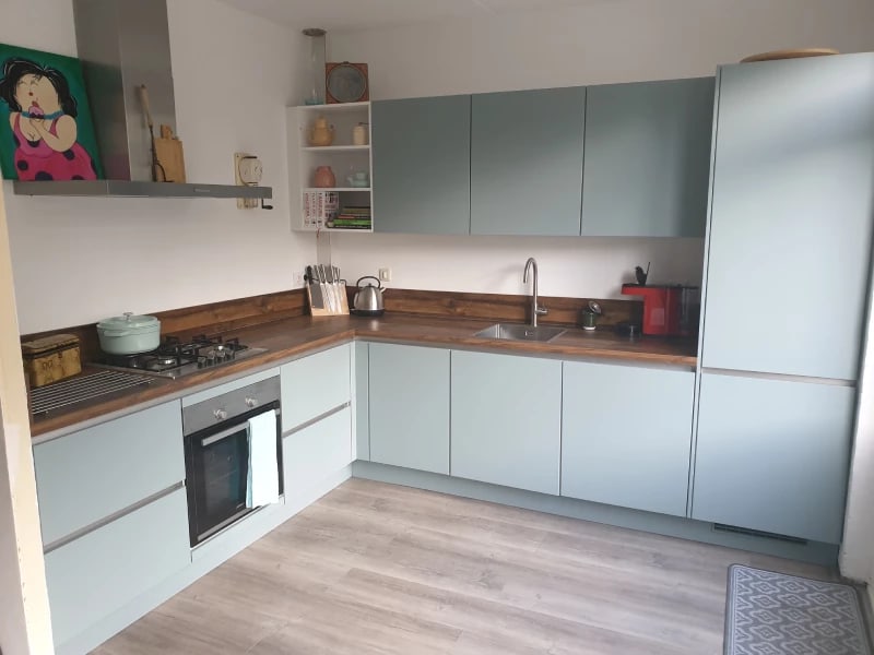 Mintgroene keuken gecombineerd met een houten werkblad