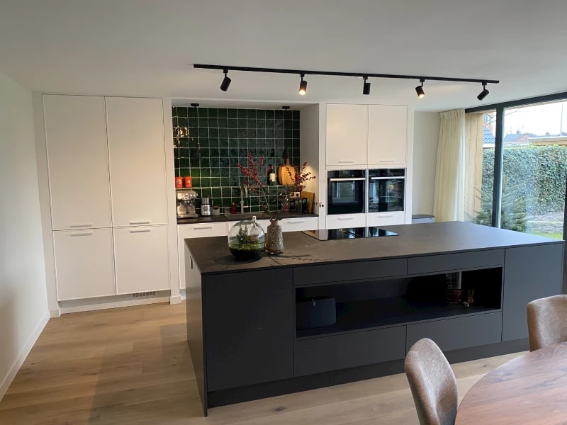 Stijlvolle woonkeuken met een donker eiland en een eettafel bij het raam